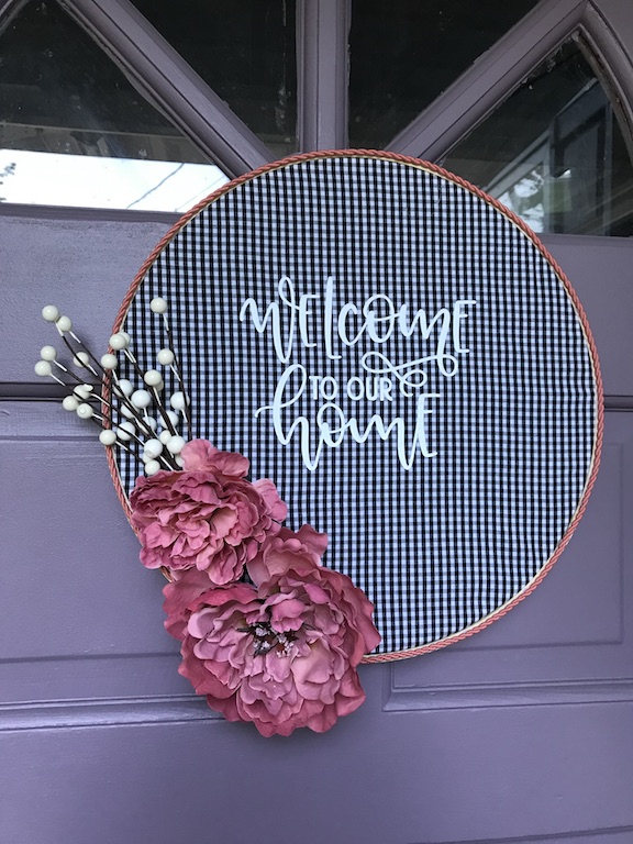 Create this DIY Buffalo Check Embroidery Hoop Wreath with an upcycle of a thrift store shirt. This welcome to our home wreath is perfect for all seasons and is a great idea for wall art or as a door hanger. #DIY #EmbroideryHoopWreath #Wreath #WallArt #DoorHanger #WelcomeSign #WelcomeWreath #NoSew #Tutorial #Fabric #Upcycle #RepurposeIt #HomeDecor #Fall #Winter #Spring #Summer #ThirftStore 