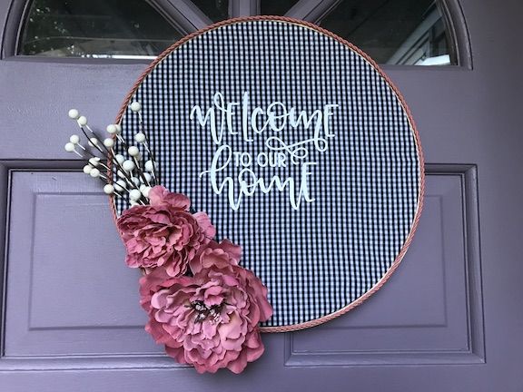 Create this DIY Buffalo Check Embroidery Hoop Wreath with an upcycle of a thrift store shirt. This welcome to our home wreath is perfect for all seasons and is a great idea for wall art or as a door hanger. #DIY #EmbroideryHoopWreath #Wreath #WallArt #DoorHanger #WelcomeSign #WelcomeWreath #NoSew #Tutorial #Fabric #Upcycle #RepurposeIt #HomeDecor #Fall #Winter #Spring #Summer #ThirftStore