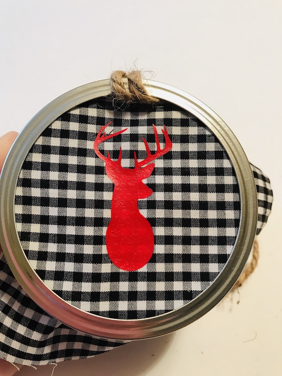 Finishing up the ornament by hot glueing the fabric to the mason jar lid