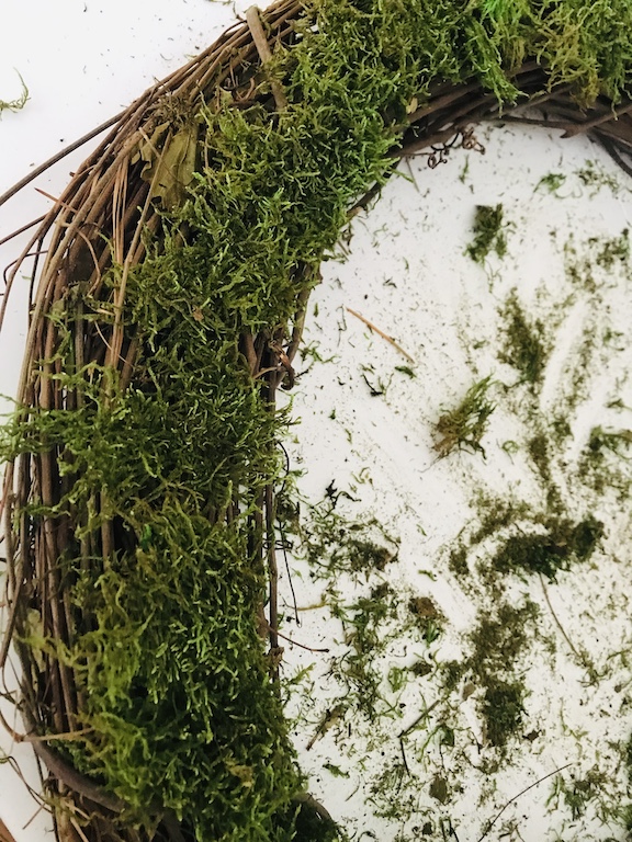 Hot glue the moss on top of the grapevine wreath 