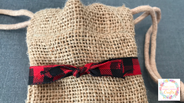 Adding Buffalo Check Ribbon to the homemade Christmas Advent Calendar with burlap bags
