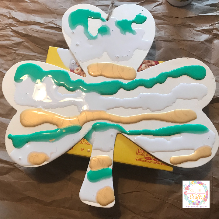 Putting premixed paint onto shamrock for easy kids paint pouring idea