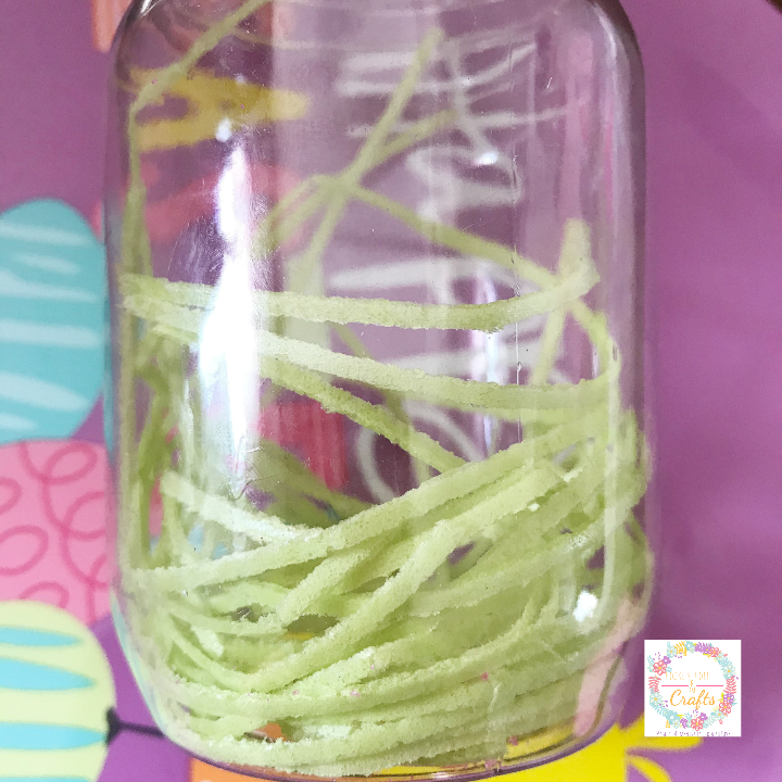 Putting Edible Easter Grass into the bottom of the candy jar 