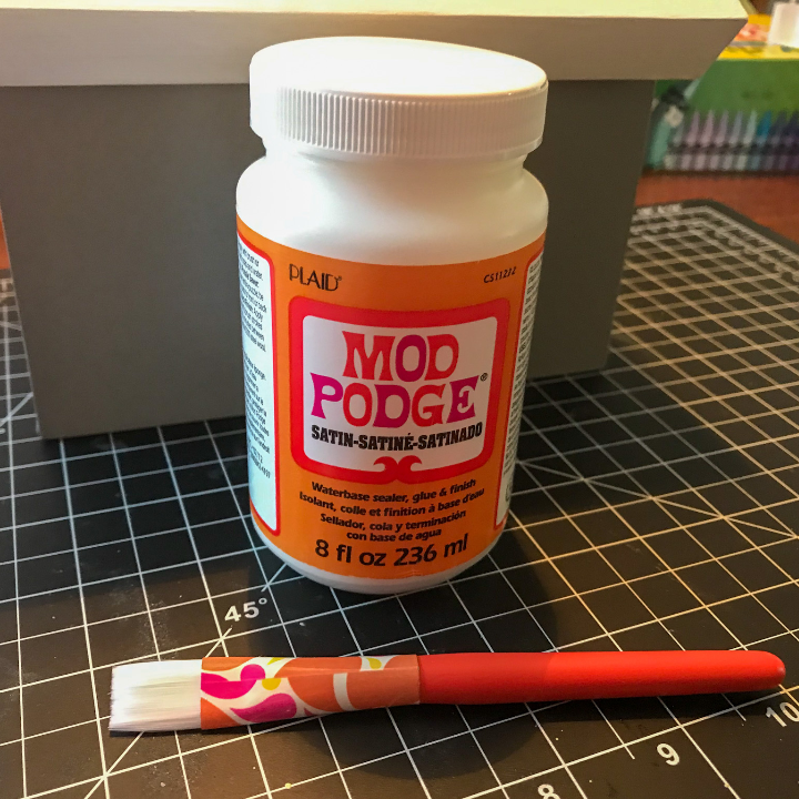 Using the Mod Podge to add the ribbon to the DIY recipe box makeover 