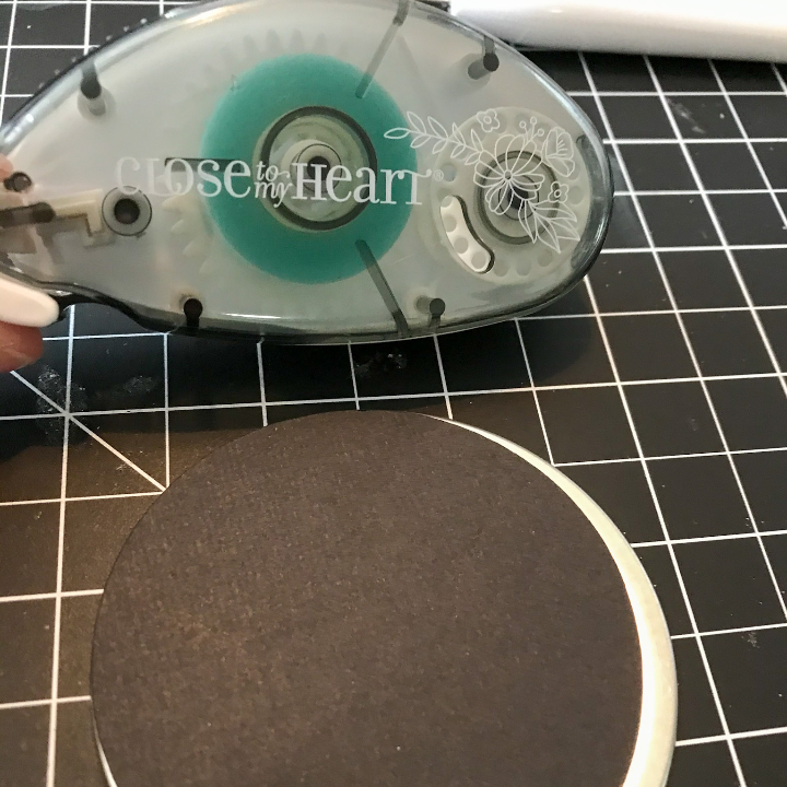 Using the tape runner to add the card stock to the mason jar lid 