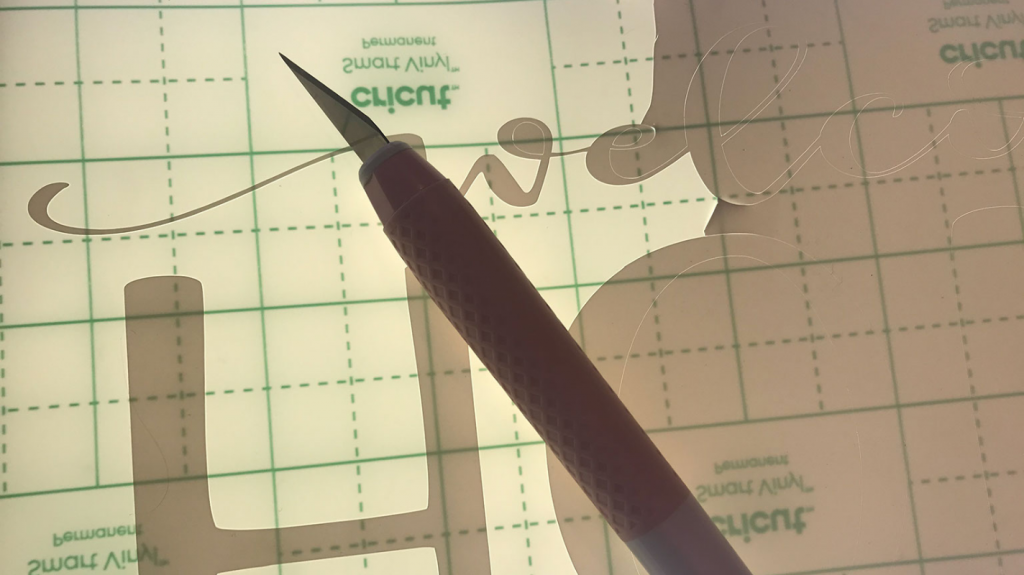 Using the Cricut true control knife to cut away extra vinyl