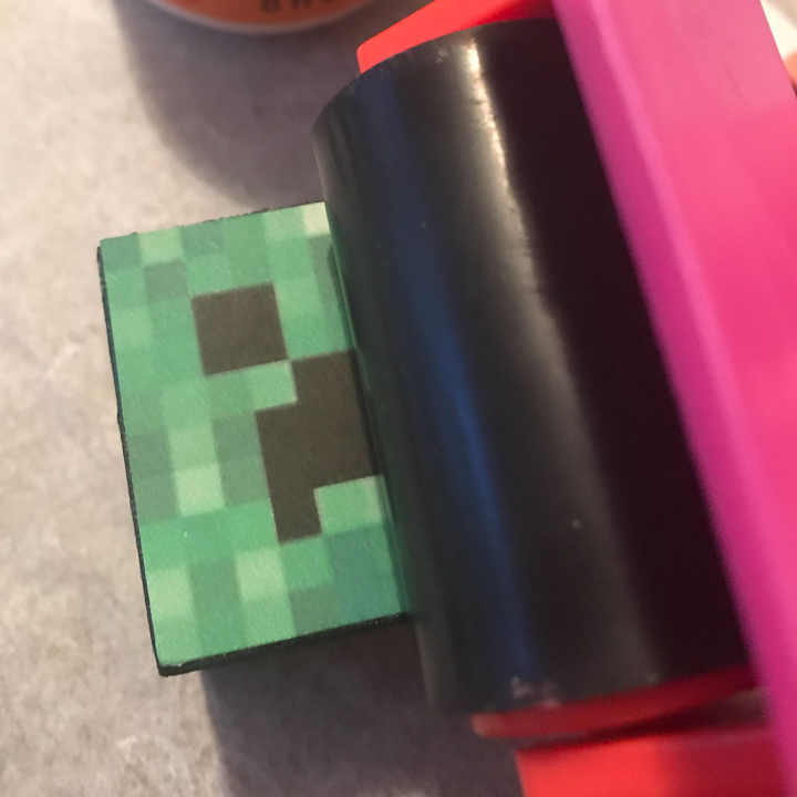 Use the Mod Podge smoothing tool to press down and adhere the Minecraft creeper face to the block 