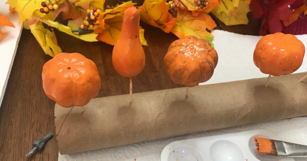 Painting the pumpkin for the fall dollar tree wreath with orange pumpkins