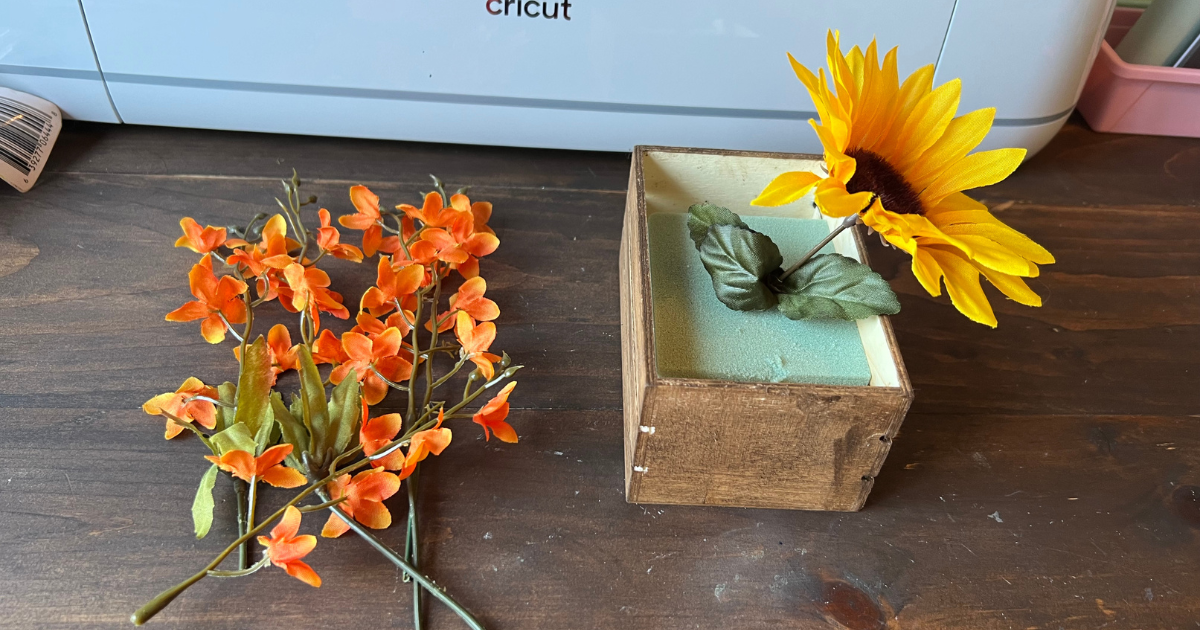 Start the Dollar Tree Sunflower centerpiece by placing one sunflower in the center of the foam