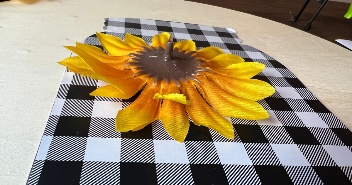 Cut the back of the stems off and hot glue the sunflowers to the wood panel